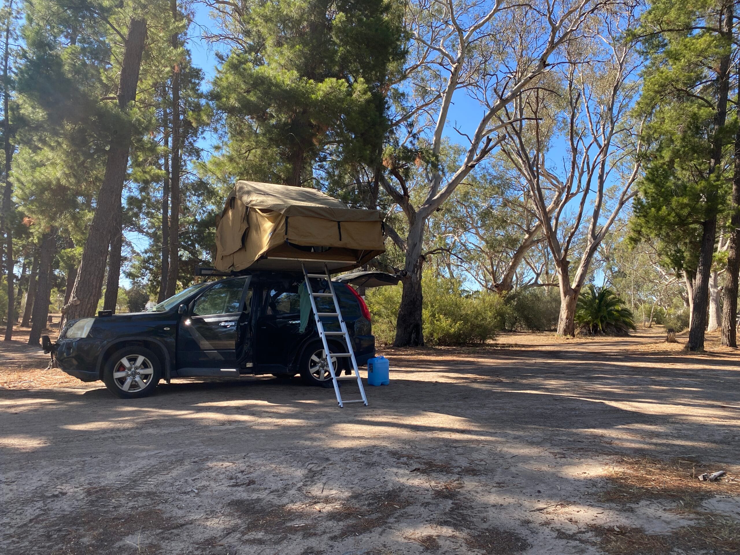 Working holiday Australia backpacker with rooftop tent camping in outback during regional work