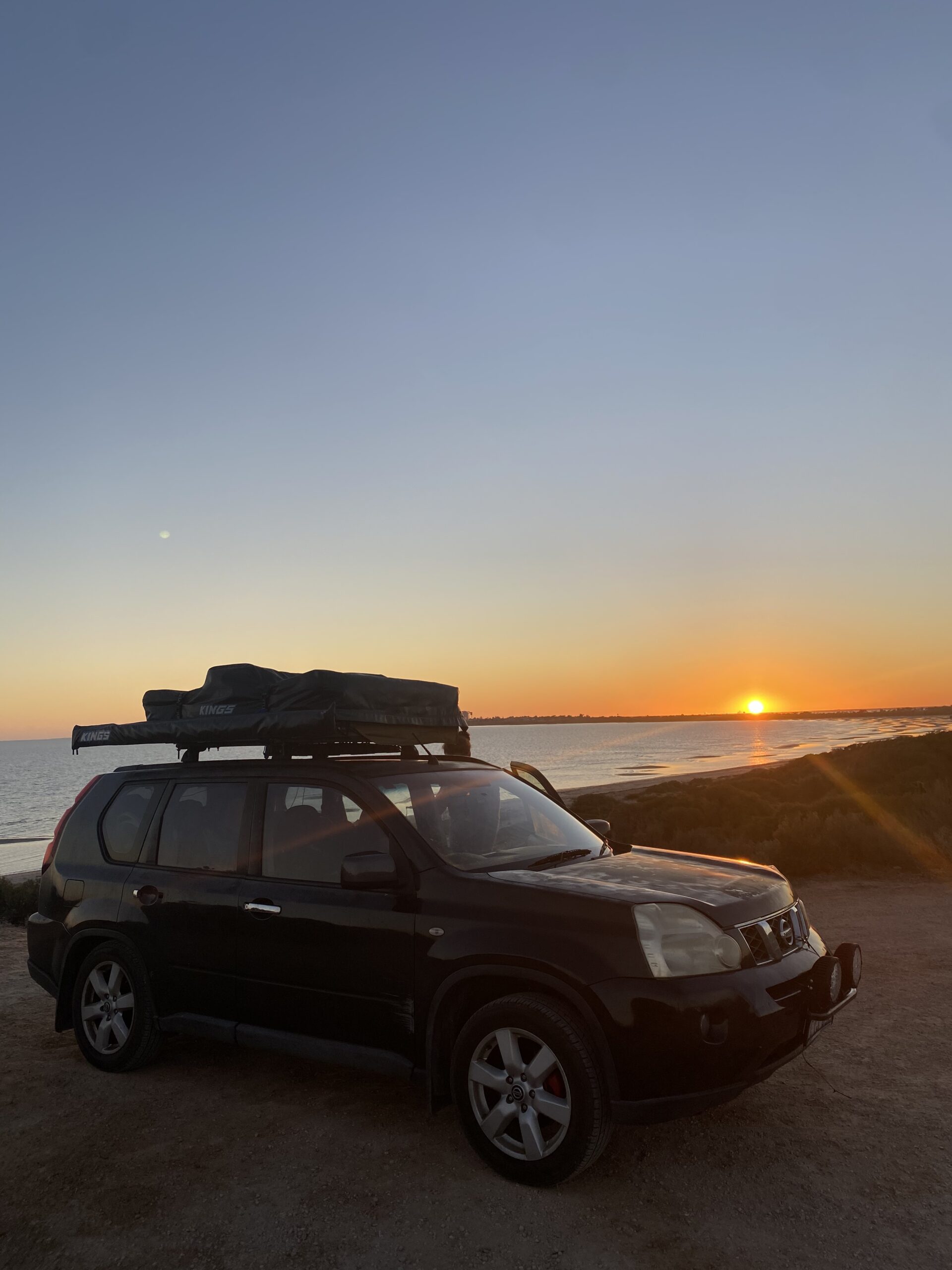 Working holiday Australia backpacker camping on beach with rooftop tent during regional work
